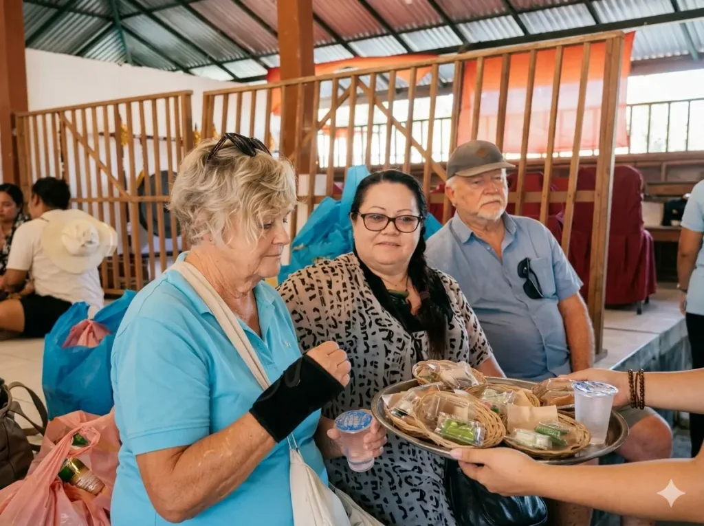 International supporters and observers seated alongside community members at Bali Sehat's free health outreach event in Tiying Tali village, with rows of blue supply bags visible behind them.