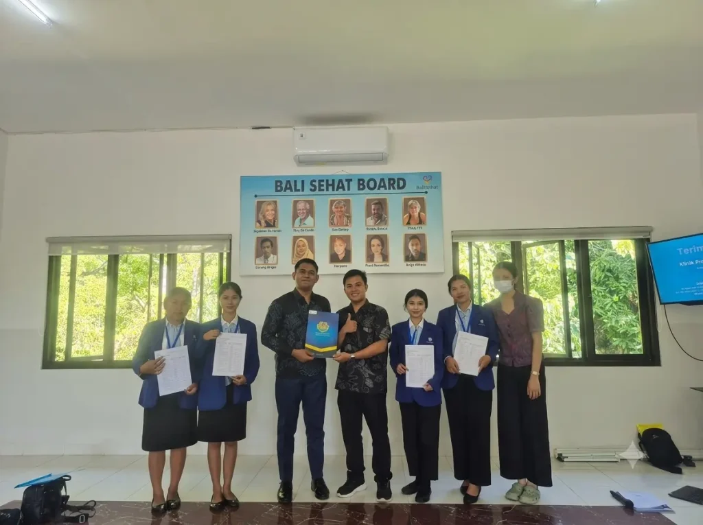 Bali Sehat Clinic staff presenting an identification badge to an on-job training student from Alfa Prima Karangasem