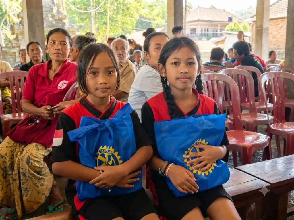 Two young girls holding Rotary donation bags during Bali Sehat Clinic's Healthy Day event in Desa Kesimpar