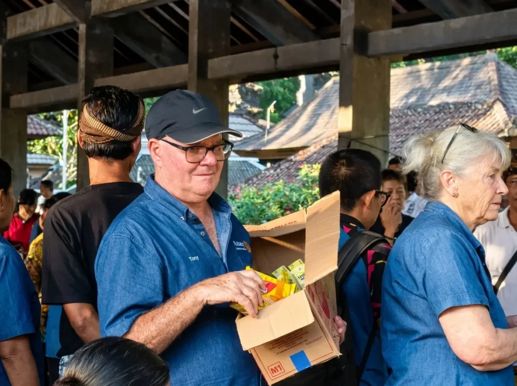 An international donor distributing donated supplies during Bali Sehat Clinic's Healthy Day event in Desa Kesimpar