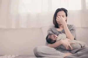 Tired new mother breastfeeding her baby while experiencing stress