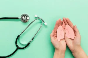 Hands holding a paper lung cutout beside a stethoscope