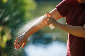Person spraying mosquito repellent on their arm outdoors