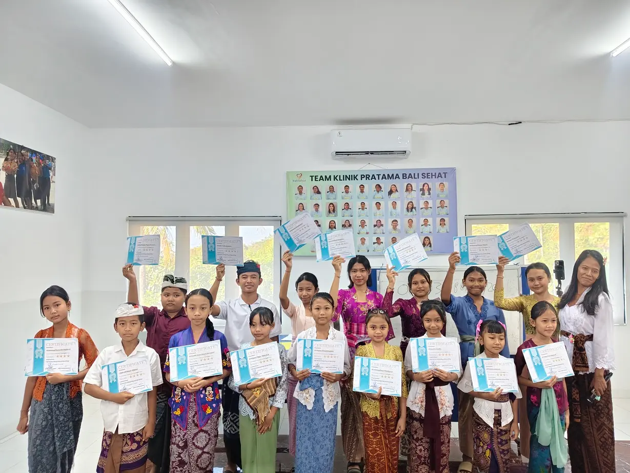 Fun English students in traditional Balinese dress holding graduation certificates