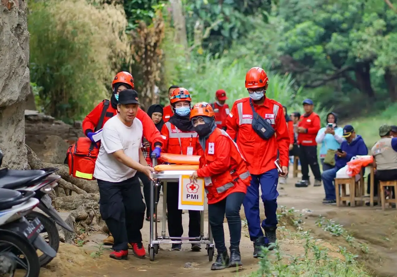 PMI volunteers carrying a patient on a stretcher along a forest path in Karangasem, East Bali