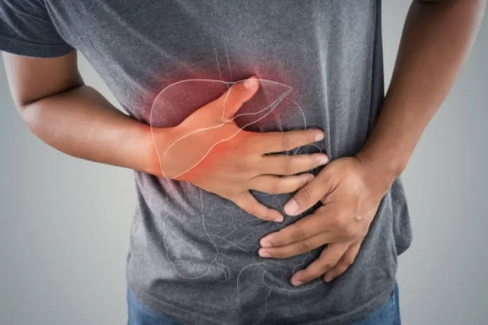Man pressing both hands to his upper abdomen, with the area highlighted in red to show pain